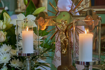 crucifixion of Christ and candles,a gilded cross in the church with the crucifixion of Jesus and two burning candles, Symbol of Christianity, faith, church