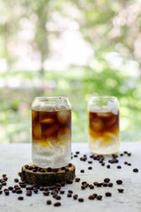 Cold black coffee with tonic and ice in glass. Summer drink on nature background