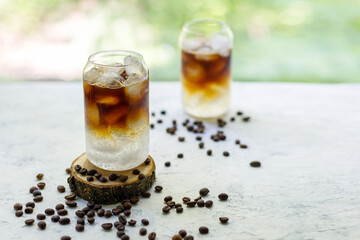 Cold black coffee with tonic and ice in glass. Summer drink on nature background
