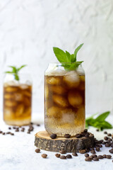 Cold summer cocktail with black coffee tonic mint and ice in glass on white background