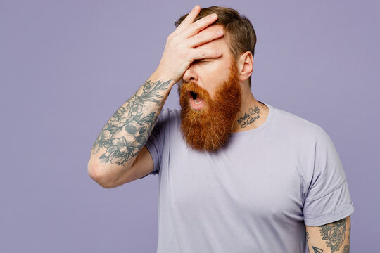 Young redhead bearded man he wearing violet t-shirt casual clothes put hand on face facepalm epic fail mistaken omg gesture isolated on plain pastel light purple background studio. Lifestyle concept.