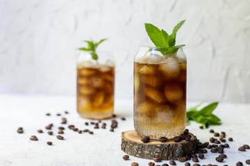 Cold summer cocktail with black coffee tonic mint and ice in glass on white background