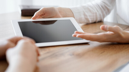 Fototapeta premium Contract papers are lying at the wooden desk while business people discussing something at the wooden desk at the background. Teamwork, partnership, contract signing concept