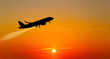 The plane takes off at sunset.