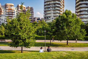 Romantic couple sitting on the grass in the park of Milano CityLife district. 