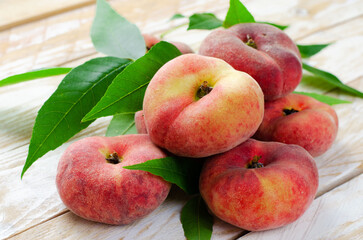 Fresh Flat Peaches, Chinese Saturn Donut Peaches with Leaves on Wooden Bright Background