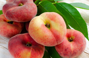Fresh Flat Peaches, Chinese Saturn Donut Peaches with Leaves on Wooden Bright Background
