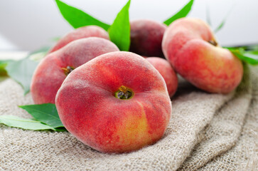 Fresh Flat Peaches, Chinese Saturn Donut Peaches with Leaves on Wooden Bright Background