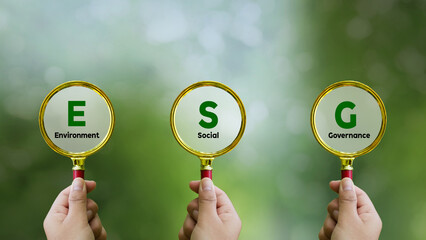 Words ESG. on magnifier glass with green backgroud. Concept of environmental, social and...