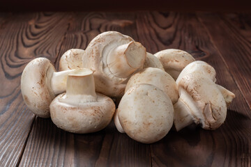 Fresh champignon mushrooms on wooden table, closeup.