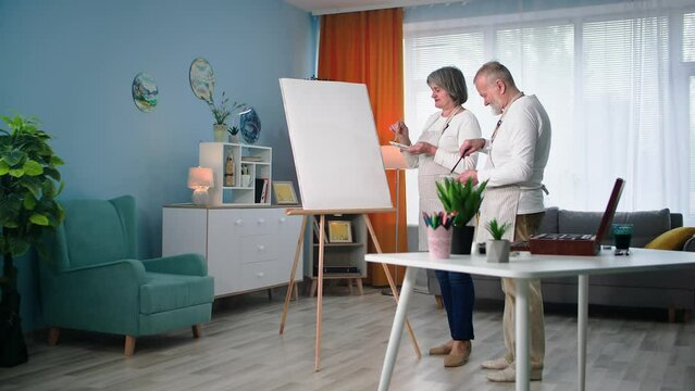 modern pensioners are fond of drawing creative pictures in retirement, old man with woman paint picture with a brush and paint at home