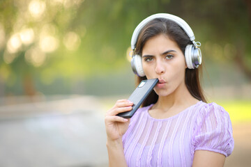 Suspicious woman looking at you listening digital audio
