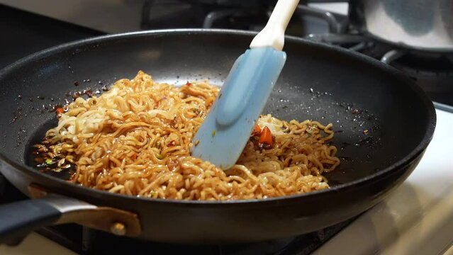 Mixing the ramen noodles in homemade sauce in the pan - slow motion