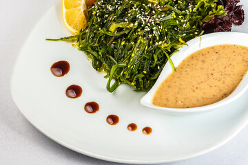 A vibrant plate of fresh vegetables and seaweed, doused in a zesty lemon sauce and sprinkled with sesame seeds - the perfect healthy meal!