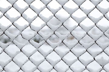 Frozen metal fence covered with snow