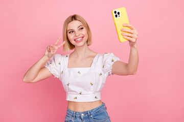 Photo of video recording selfie blogging lady have fun showing v-sign hold phone promo apple brand sale isolated on pink color background