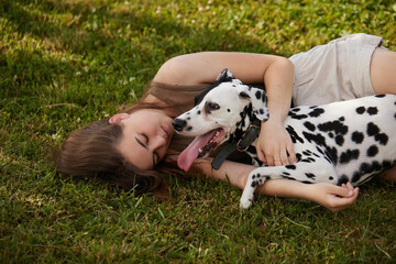 a young girl plays with a dalmatian in the park. dog care concept