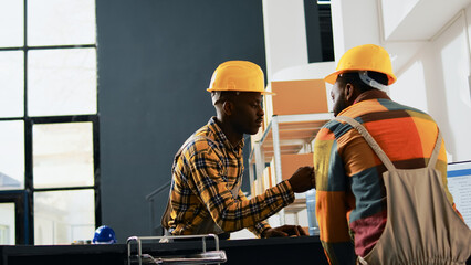 Young depot workers doing fist bump sign in storehouse, greeting each other at work. Team of people...