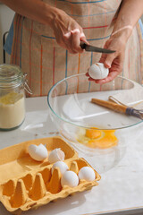 top view of woman beating eggs for an omelette or pie. Cook delicious and healthy food at home for breakfast. A whisk or mixer for convenience of cooking protein dish. broken eggshells and paper box