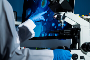 Close-up of scientist's hand observing specimen with microscope