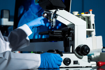 Close-up of scientist's hand observing specimen with microscope