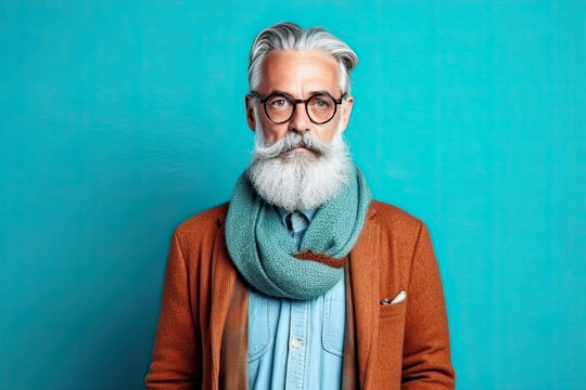 Studio shot of handsome senior man hipster dressed in stylish coat and sunglasses. Isolated on blue background