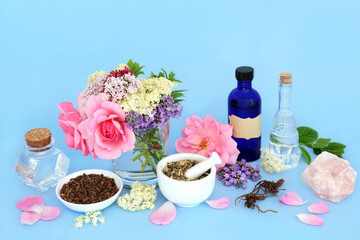 Flowers and herbs used in natural alternative herbal medicine remedies. Medicinal sedative food ingredients with rose quartz crystal for healing. On blue background.