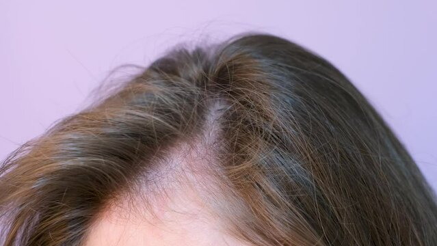 Girl touching her hair close-up on light pink background, hair loss concept.