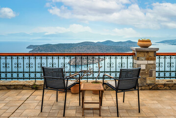 Sea view terrace adorned with garden furniture. Two chairs and a small wooden table, creating a...