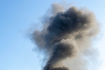 Emergency helicopter recharging water to extinguish a forest fire thick black smoke rises into the blue sky. Smoke from fire. Disaster. High quality photo