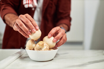 A man's hands, take mushrooms from a bowl after cleaning it with water.
