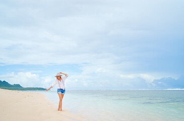 Fototapeta na wymiar Vacation on the seashore. Young woman walking on the beautiful tropical white sand beach.