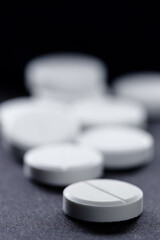 Obraz na płótnie Canvas Medicine and drug concept. Macro shot of white tablets bunch on black background.