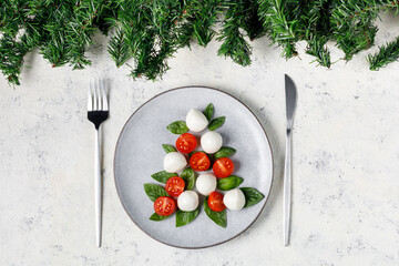 Caprese salad in the form of a Christmas tree. Festive tomato mozzarella and basil appetizer on...