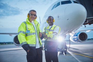 Portrait confident air traffic control ground crew workers near airplane on airport tarmac