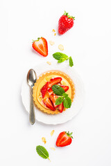 Flat lay composirion with strawberry mini cake tartlet with vanilla custard, sprinkled with almond flakes and mint leaves over white background. Concept of homemade healthy sweet pastries. Top view