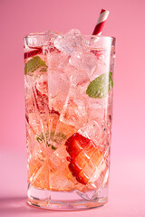 Fresh healthy limonate cocktail with crushed ice, strawberry and mint on pinkbackground. Summer cold drink concept, close up shot