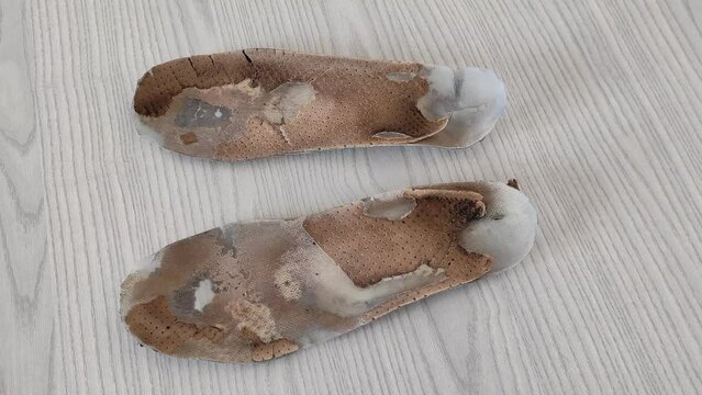 Old worn orthopedic insoles. Dirty leather insoles. Worn out things with holes. Insoles of shoes.