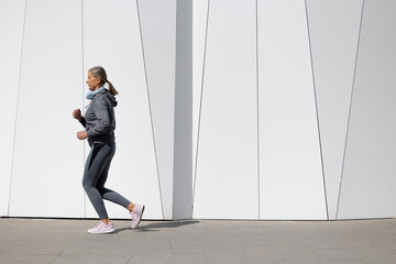 Fototapeta na wymiar Woman in grey sportswear exercising and looking energetic
