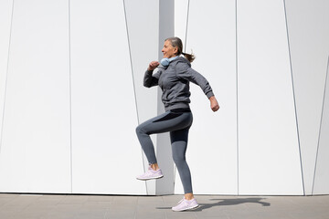 Woman in grey sportswear exercising and looking energetic