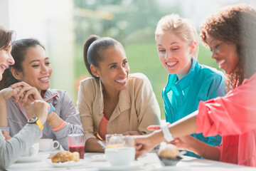 Women talking and looking at smart watch at cafe table post workout