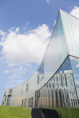 Modern building with reflection under sunny blue sky with clouds