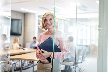 Portrait smiling businesswoman in conference room doorway
