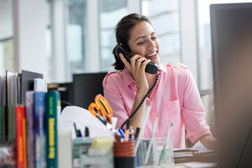 Smiling businesswoman talking on telephone working at computer in office