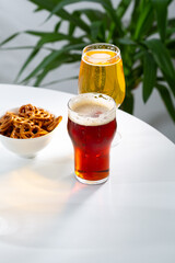 Two glasses with cold beer snack food and drink on light table