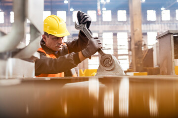 Steel worker using large wrench in factory - obrazy, fototapety, plakaty