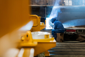 Welder using welding torch in steel factory - obrazy, fototapety, plakaty