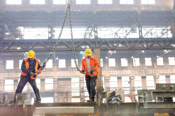 Steel workers with crane hooks in factory - obrazy, fototapety, plakaty
