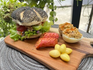 Tuna salad bagel burger with devil egg and grilled pink sausage 