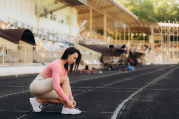 Fototapeta na wymiar Runner women tying shoes laces getting ready for race on run track in stadium sport and fitness concept.